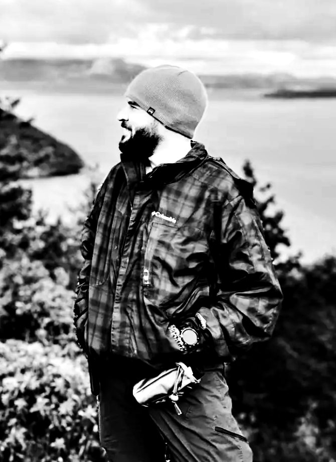 André in a beanie and a plaid jacket, looking out over the water